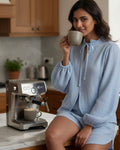 Woman in a kitchen holding a coffee cup with an espresso machine in the background